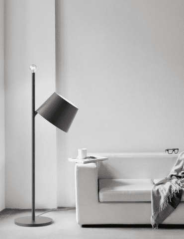 A minimalist living room with a white sofa, a gray floor lamp with an inclined lampshade and warm accents, as elegantly stylized as the Evalo WP model, perfect for those who appreciate the sleek design and calm spaces.